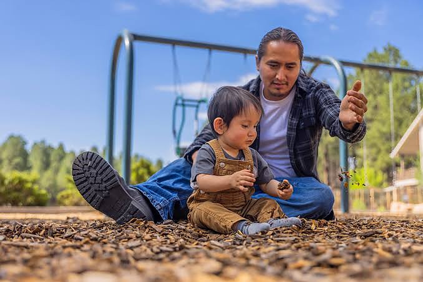 An adult and a toddler playing at a playground